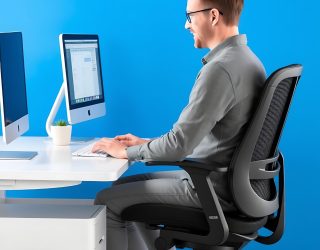 Trabajador sentado correctamente en una silla ergonómica frente a una computadora
